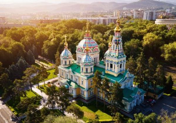 aerial-drone-panorama-of-the-ascension-cathedral-russian-orthodox-church-and-snow-mountains-at-background-in-panfilov-park-at-glow-sunrise-light-in-almaty-city,-kazakhstan
